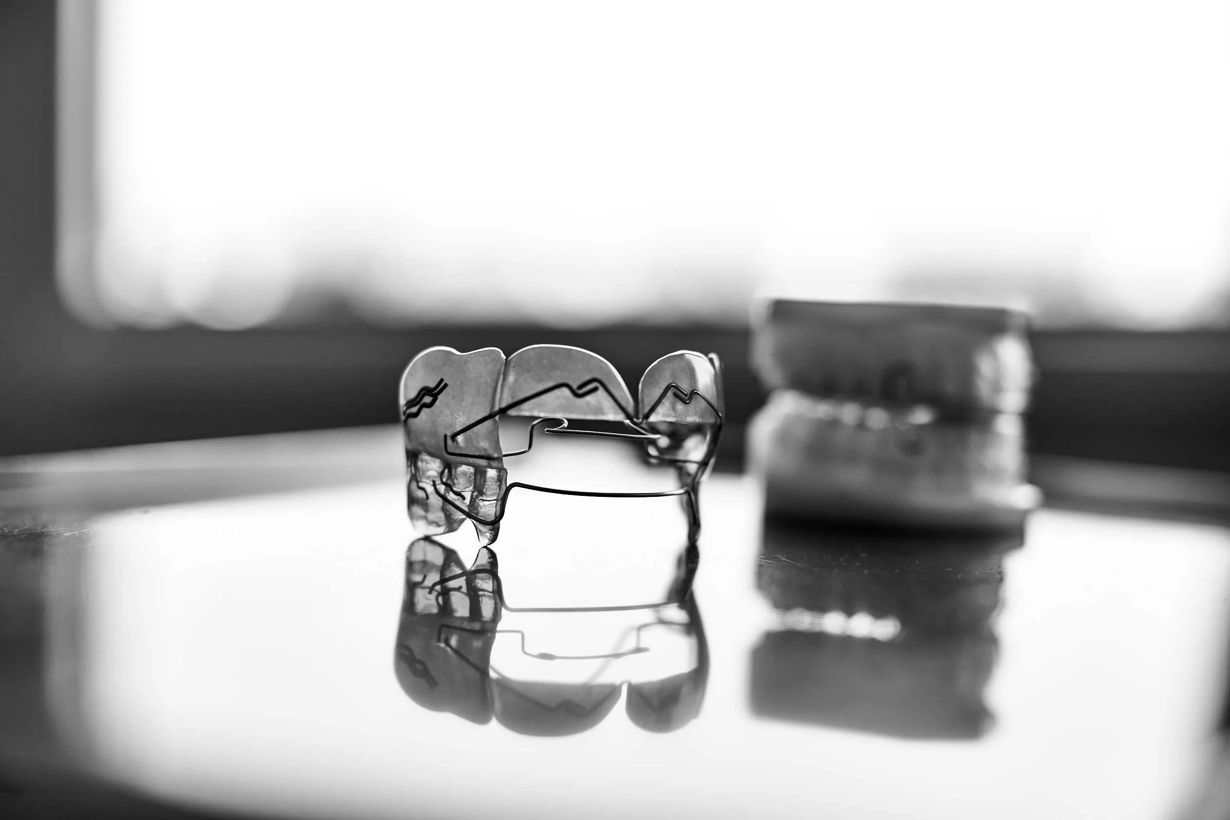 Herausnehmbare Zahnspange liegt auf einem Tisch. Daneben ist ein Gipsmodell  des Gebisses.